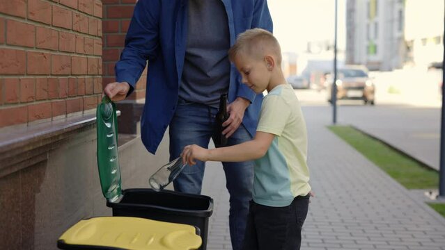 Dad teaches his son to properly sort garbage. Father and son sorting the glass properly. Ecology and environmental problems concept