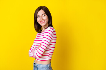 Photo portrait of cheery confident young girl look empty space crossed arms wear trendy striped garment isolated on yellow color background