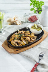 Fried potatoes with mushrooms and pickles on white table background