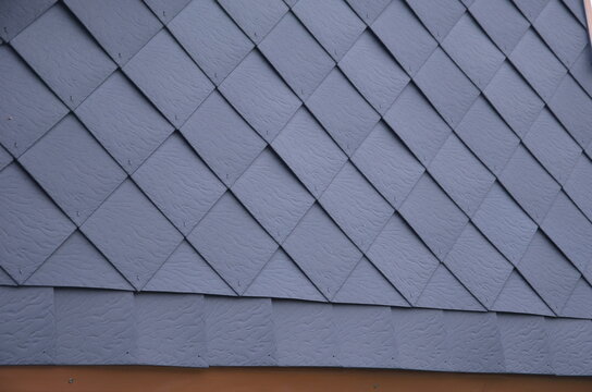 covering the wall of the house from square tiles hammered onto a wooden grid. the ventilated wall protects against moisture and frost in mountain conditions. ridges of mountains