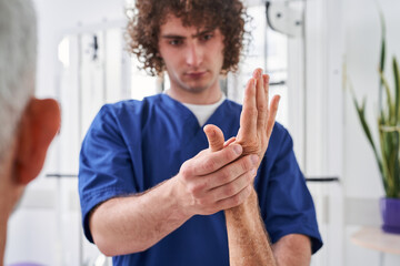 Male specialist making massage of old patient during the treatment