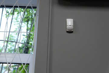 Modern motion sensor on wall indoors.