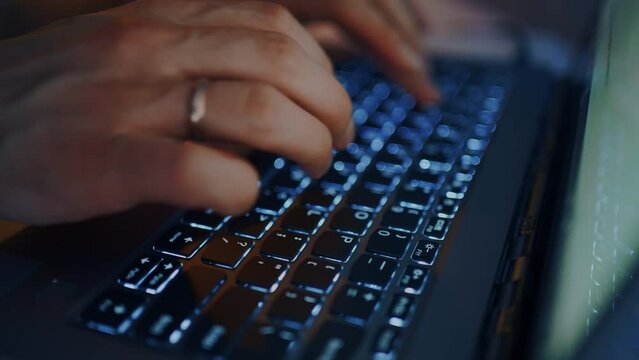 man is typing message and text on keyboard of laptop, closeup view of fingers, illuminating keys