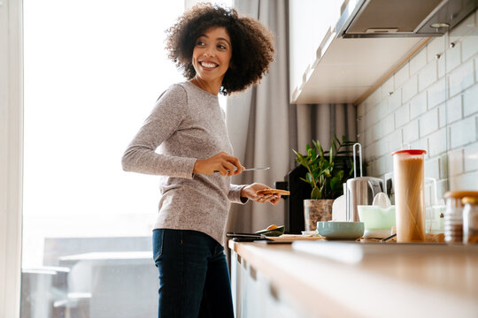 African American Young Woman Making Breakfast In Morning At Home