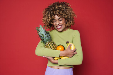 Young black woman laughing while posing with fruits