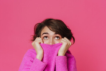 White young woman looking upward while hiding in her sweater