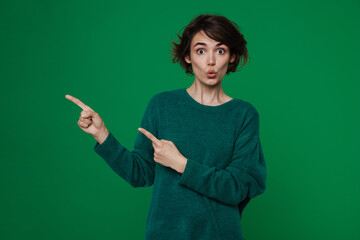 Young woman expressing surprise while pointing fingers aside