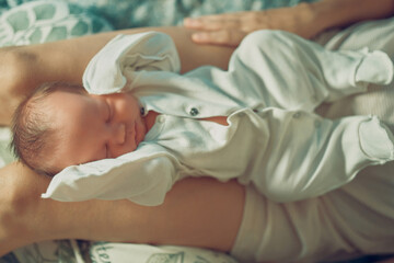 Obraz na płótnie Canvas A newborn baby is lying on his mother's lap