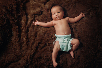 portrait of a newborn baby lying on a brown fur blanket