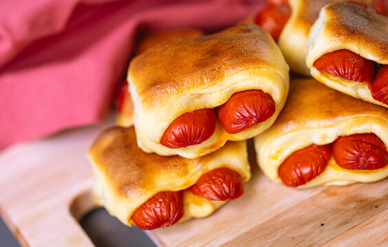 Cachorro-quente assado com massa de p&atilde;o (hot dog s&iacute;rio) ou enroladinho de salsicha na massa de p&atilde;o. Salgado tradicional no Brasil. Comida brasileira. Cachorro quente.