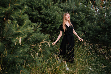 beautiful young girl in black dress and with long hair is resting in nature