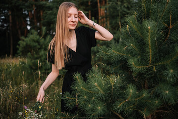 Naklejka premium beautiful young girl in black dress and with long hair is resting in nature