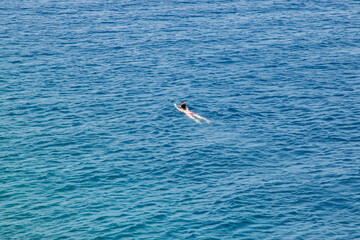 Fototapeta na wymiar Girl swimming in clear blue sea waters in sunny summer day