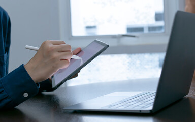 Closeup hand businessperson using tablet and laptop writing,signing or analyzing.