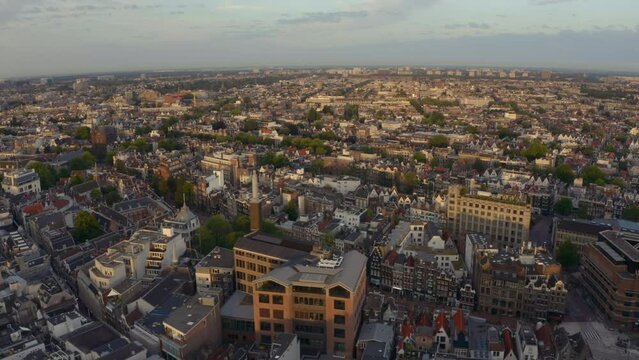 Slider drone shot over central Amsterdam Damrak at sunrise golden hour