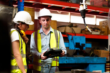 Two maintenance engineers men and women inspect relay protection system with laptop comp. They work a heavy industry manufacturing factory.