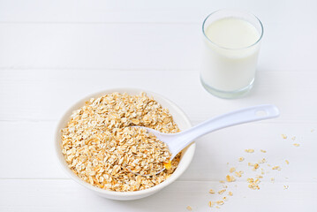 bowl of granola with a spoon and a glass of oat milk. white wooden background. top view. copy space.