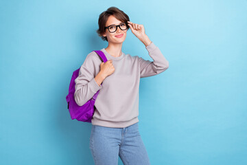 Portrait of pretty cheerful smart girl nice outfit hold bag touch eye accessory stand empty space isolated on blue color background