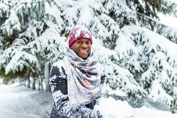 african american man in a snowy winter woodland with snowflakes falling from spruce and fir forest