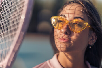 Chica joven con septum y conjunto de tenis rosa en cancha de tenis con raqueta