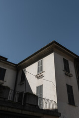 Historic Italian architecture. Traditional European old town street building in sunlight shadows. Wooden windows, shutters and neutral color walls. Aesthetic summer vacation travel background