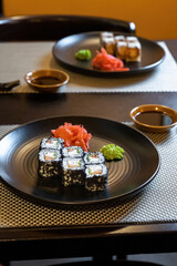 Close-up of fresh rolls and sushi set, with salmon, sprinkled with black caviar. Plate in the middle of the composition. Vertical photo