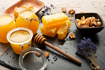 Honeycomb on slate tray with honey and nuts on kitchen table