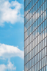 Fototapeta na wymiar glazed facade of a high-rise building against a blue sky with clouds