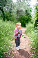Little girl blowing soap bubbles standing in the park. High quality photo