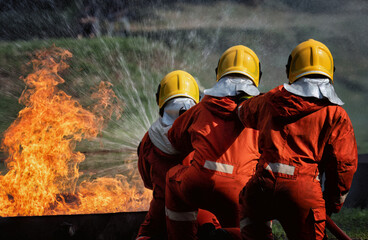 In Industry safety fire fighter team department on  training fight with gas and oil fire by hold hose together spray jet turbulence water and foam to extinguish remove oxygen
