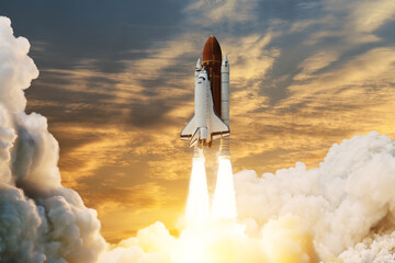 Spaceship lift off. Space shuttle with smoke and blast takes off into space on a background of sunset. Successful start of a space mission. Elements of this image furnished by NASA. - obrazy, fototapety, plakaty