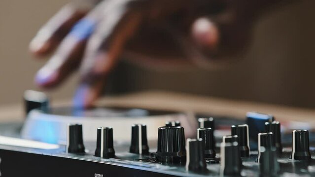 Close-up male hands spin disc on DJ panel unknown man African musician playing live electronic hip hop dance music on party in club spinning twist vinyl on mixer controller desk create modern remix
