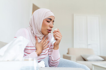 Arabic woman is having flu . Sick with a rhinitis womanwith hijab has dripping nose. Woman being sick having flu lying on sofa.
