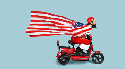 Santa with a big flying usa flag in the form of a raincoat and a helmet rides a red electric...
