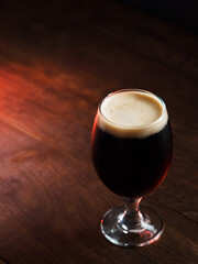 glass of dark craft beer on a wooden table