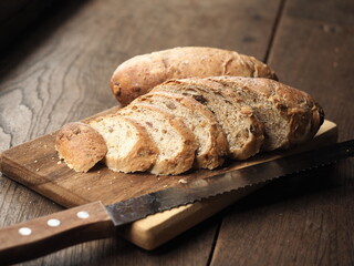 Sliced whole wheat bread with mix seed and dried fruit on wooden cutting board with knife