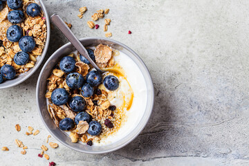 Fototapeta na wymiar Breakfast yogurt bowl with granola, blueberries and maple syrup, gray background.