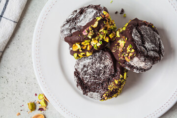 Chocolate cookie ice cream sandwiches covered with dark chocolate and pistachios, top view.