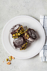 Chocolate cookie ice cream sandwiches covered with dark chocolate and pistachios, top view.