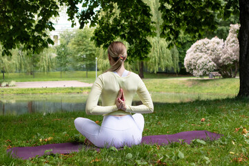 young girl doing yoga in the park in nature in summer