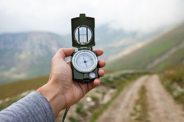 Hand with a compass on a mountain road © ARAMYAN