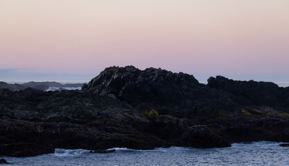 Fototapeta na wymiar Rugged Rocks on a rocky shore on the West Coast of Pacific Ocean. Summer sunrise. Ucluelet, Vancouver Island, British Columbia, Canada. Nature Background
