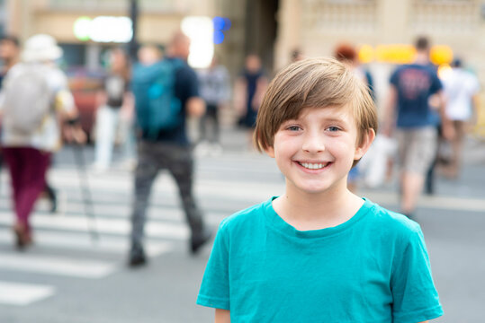 portrait of a happy boy. the child is about to cross the road on a pedestrian crossing or zebra crossing. schoolboy in front of the road and crowds of people crossing the roadway