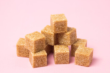 Cane sugar on a pink background. Brown refined cane sugar.