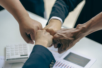 Successful colleagues put their naughty hands with fists together in the financial business idea office.