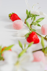 Branch composition with flowers, strawberries and candies. Food styling. Spring comfort food composition.