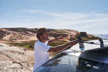 Caucasian male surfer and camper packing and unpacking from car's roof