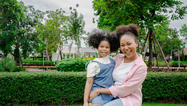 Beautiful African American Mother And Daughter Smiling Happy And Hugging. Standing With Smile On Face Standing At The Park Nature.Summer Activity And Happy Mother Day.