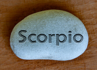 Scorpio zodiac sign text engraved on a stock with wooden background. Zodiac sign concept