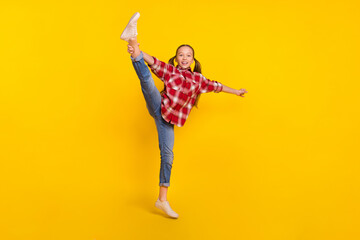 Photo of excited sweet schoolgirl wear checkered shirt jumping high dancing rising leg isolated...
